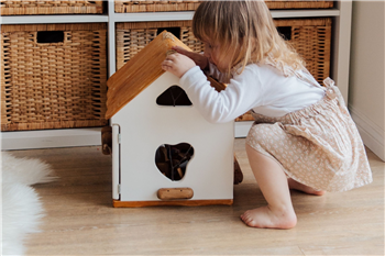 girl looking into toy house