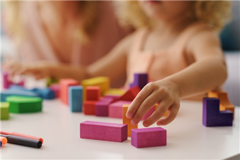 mother or carer with a child playing with some coloured blocks